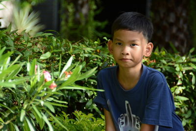 Portrait of boy standing by plants in park