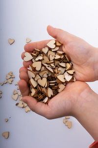 Cropped hand of person holding roasted coffee beans against white background