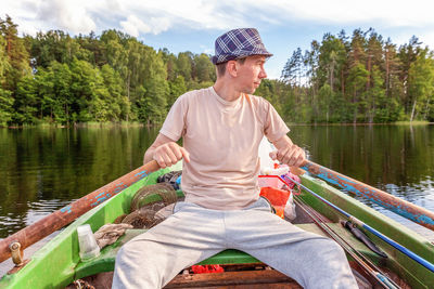 Rear view of man sitting in boat in lake