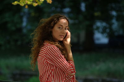 Portrait of beautiful woman with tousled hair standing in park