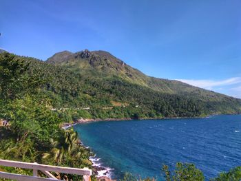 Scenic view of sea and mountains against clear blue sky