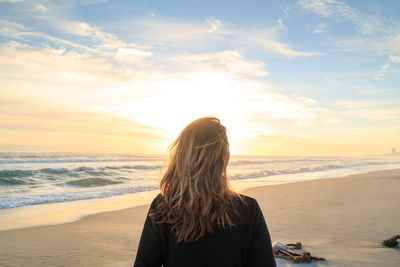 Rear view of woman on beach at sunset