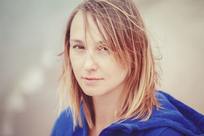 Close-up portrait of woman with tousled hair standing outdoors