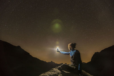 Man standing on rock against sky at night