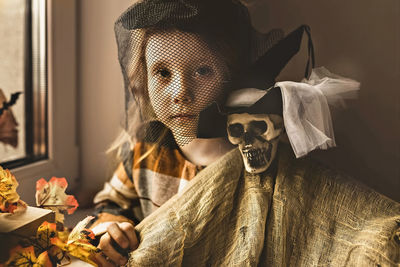 Portrait of young woman standing by window on the halloween decorations 