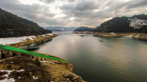 Scenic view of lake by mountains against sky