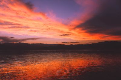 Scenic view of lake against dramatic sky during sunset