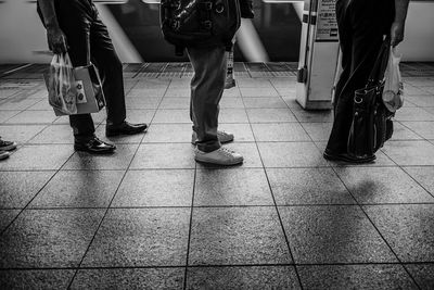 Low section of people walking on tiled floor
