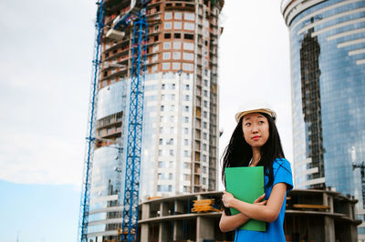 Female architect standing against incomplete building