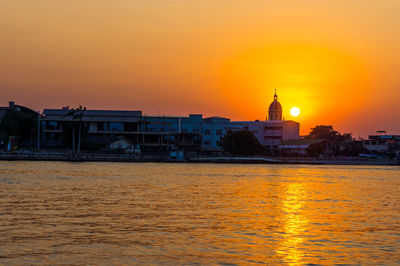 Buildings at waterfront during sunset