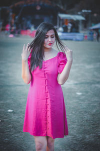 Beautiful young woman standing against pink petals