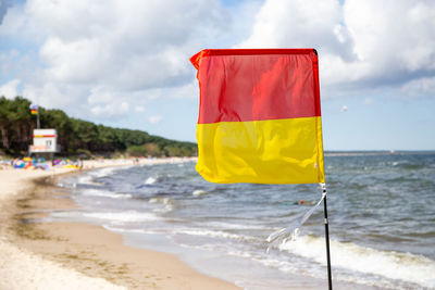 Yellow flag on beach against sky