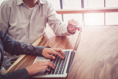 High angle view of businessman assisting secretary using laptop at desk