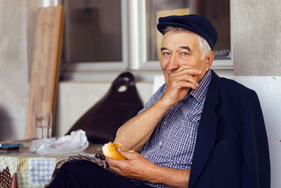 Portrait of senior man cleaning face while sitting by table outdoors