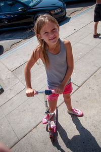 Full length portrait of girl on push scooter in city