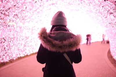 Rear view of woman standing against pink during winter