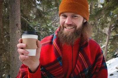 Walk with a cup of hot cocoa in the winter park. portrait of a handsome bearded guy in winter