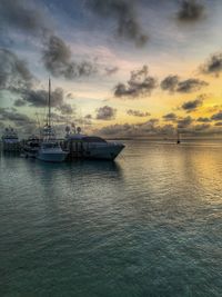 Boats moored on sea against sky during sunset