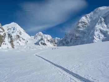 Diminishing perspective of ski tracks on glacier from mountaineering rope team with mountains