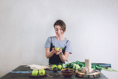 Smiling young woman holding ice cream in basket on table