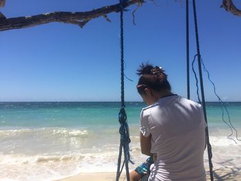 Rear view of man on beach against sky