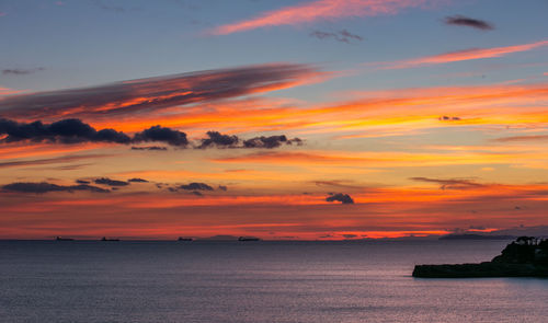 Scenic view of sea against dramatic sky during sunset