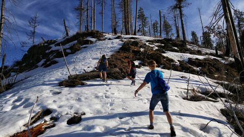 Low angle view of people hiking on snowcapped mountain during sunny day