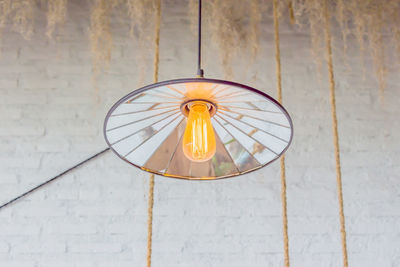 Low angle view of illuminated light bulb hanging on ceiling