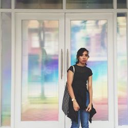 Portrait of young woman standing against closed door