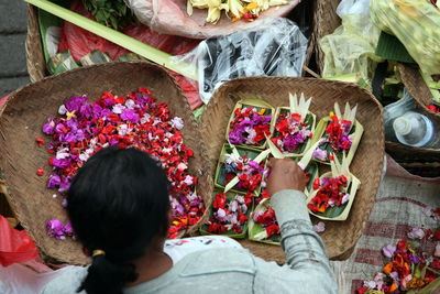 High angle view of female vendor making flower garlands on street market