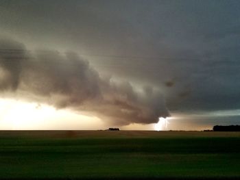 Scenic view of field against storm clouds