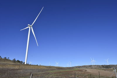 Wind turbines on field against clear blue sky