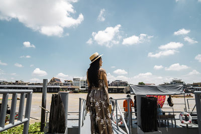 Woman standing against lake in city against sky