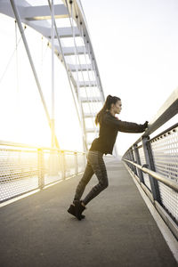 Woman standing on footbridge against sky