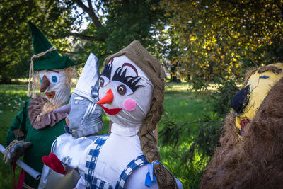 Close-up of scarecrows on field against trees