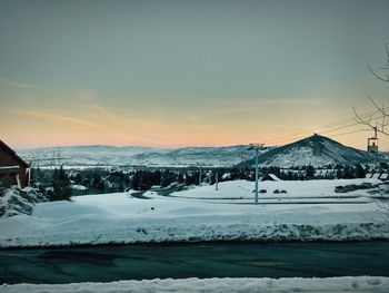 Snow covered landscape against sky during sunset