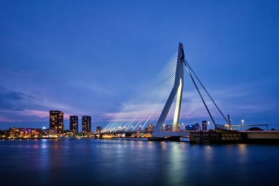 Illuminated bridge over river against sky in city at night