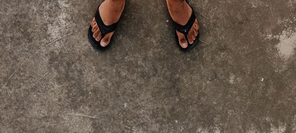 Low section of man standing on concrete floor