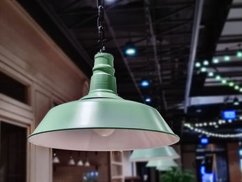 Low angle view of illuminated pendant light hanging in building