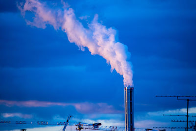 Smoke emitting from factory against sky