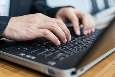 Midsection of man using laptop on table