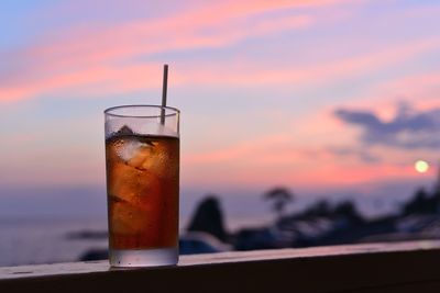 Close-up of iced tea on retaining wall against sky