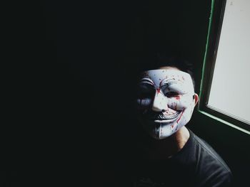 Portrait of man with mask sitting by window