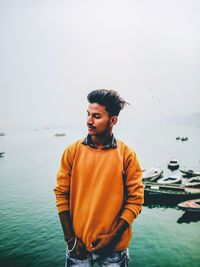 Young man standing in sea against sky