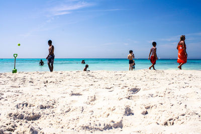 People enjoying at beach against sky