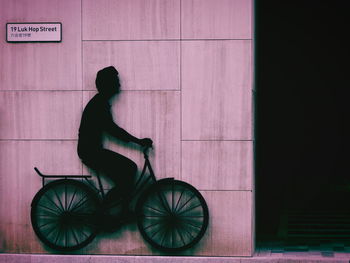 Side view of woman riding bicycle against wall