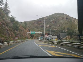 Road leading towards mountains seen through car windshield