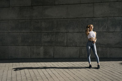 Full length of woman standing against wall