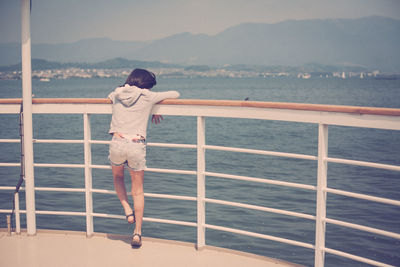 Rear view of girl standing on ship in river against sunny day