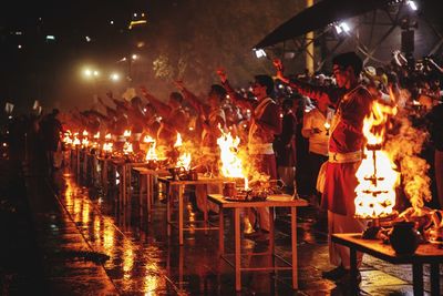 People standing against illuminated fire at night
